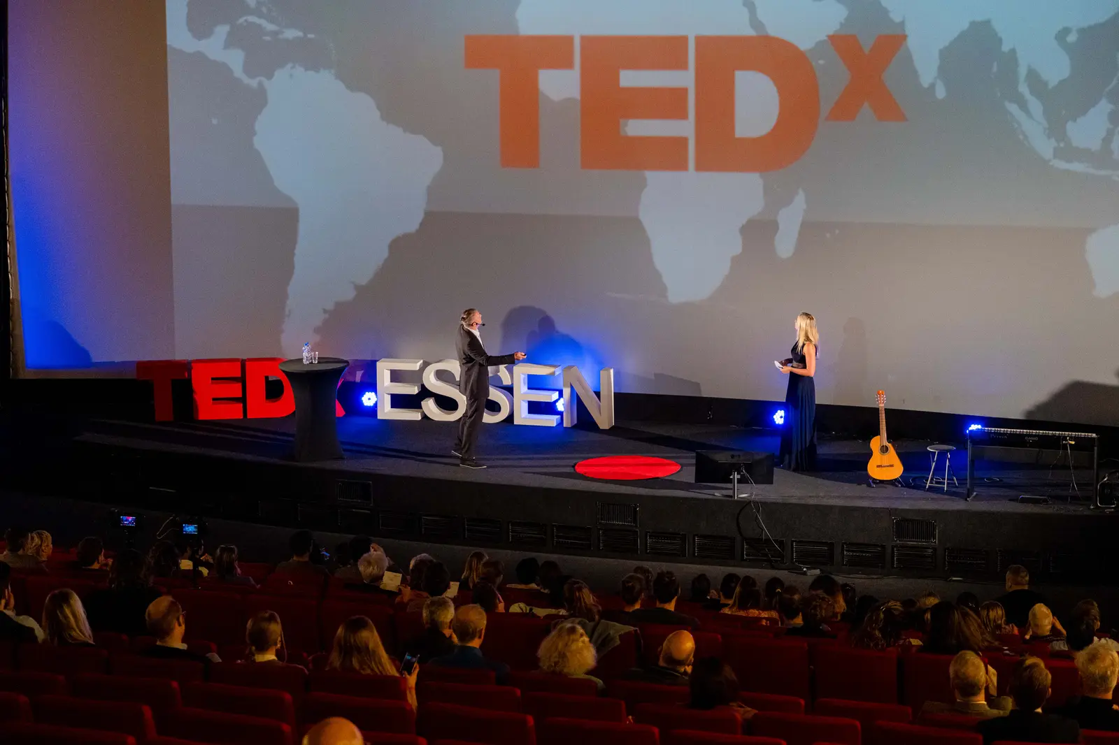 Wide view of the stage with the TEDx logo on the screen
