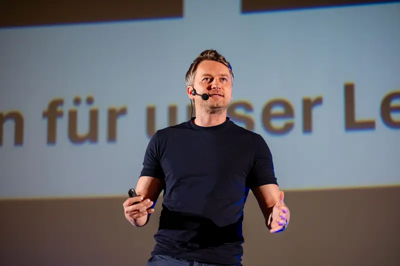 Speaker in a black T-shirt mid-talk with a clicker